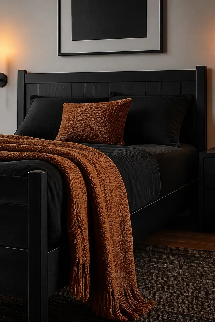 Black bed with cognac throw blanket and warm amber bedside lamps