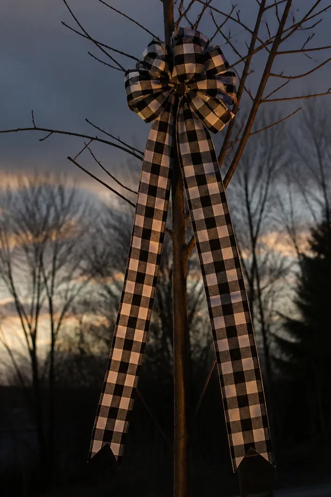 Black and white buffalo plaid ribbon tails hanging from an outdoor evergreen tree