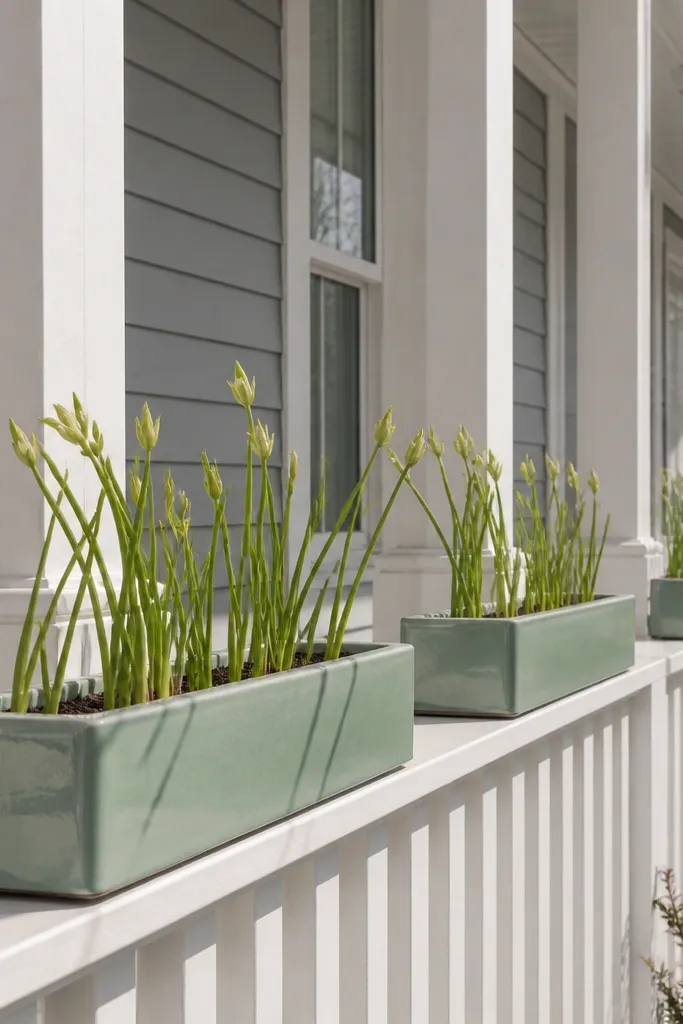 Mint glazed railing planters with pale green stems along a front porch railing