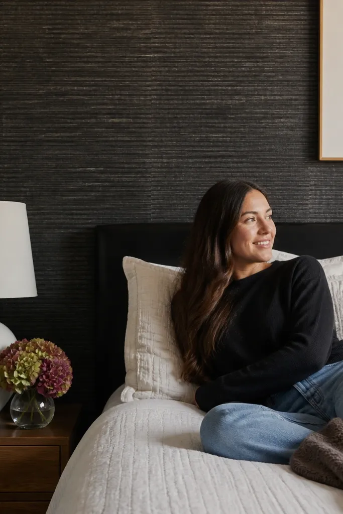 Black textured grasscloth-style wallpaper on an accent wall behind a bed