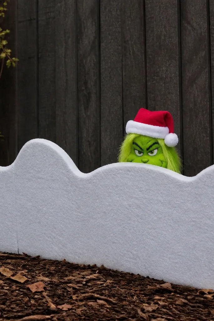 White snowdrift panel with a small Grinch peeking from the bottom of a fence